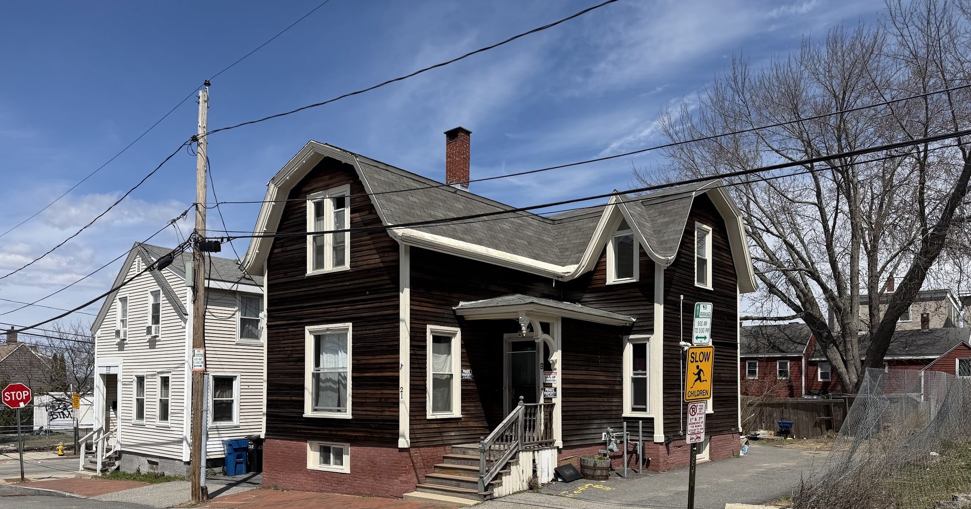 Street-level view of 21 Cedar — dark-stained single-family with front dormers.